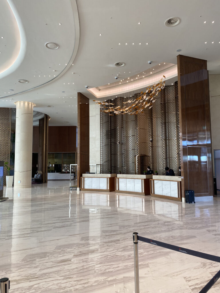 The first-floor lobby. High ceilings, gold lattice decoration, and a row of front desks