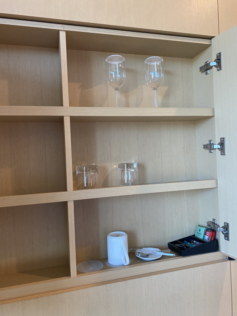 The cabinet. Wine glasses, cups, mugs, and tea bags, neatly arranged