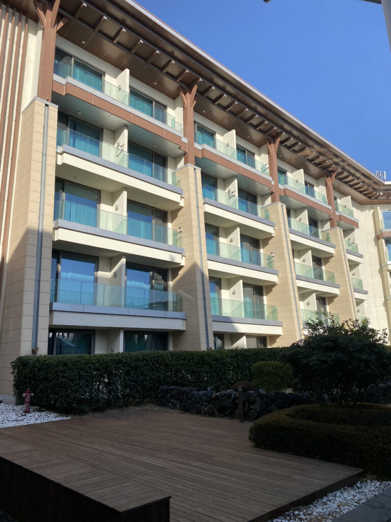 The hotel exterior. Glass balconies stacked floor by floor, and the deck
