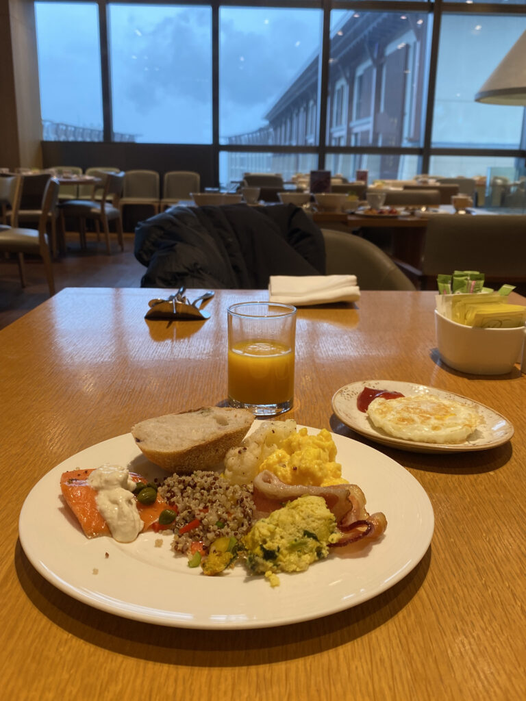 First plate. Bread, scrambled eggs, salmon, quinoa, bacon, cauliflower. Orange juice comes as basic setting