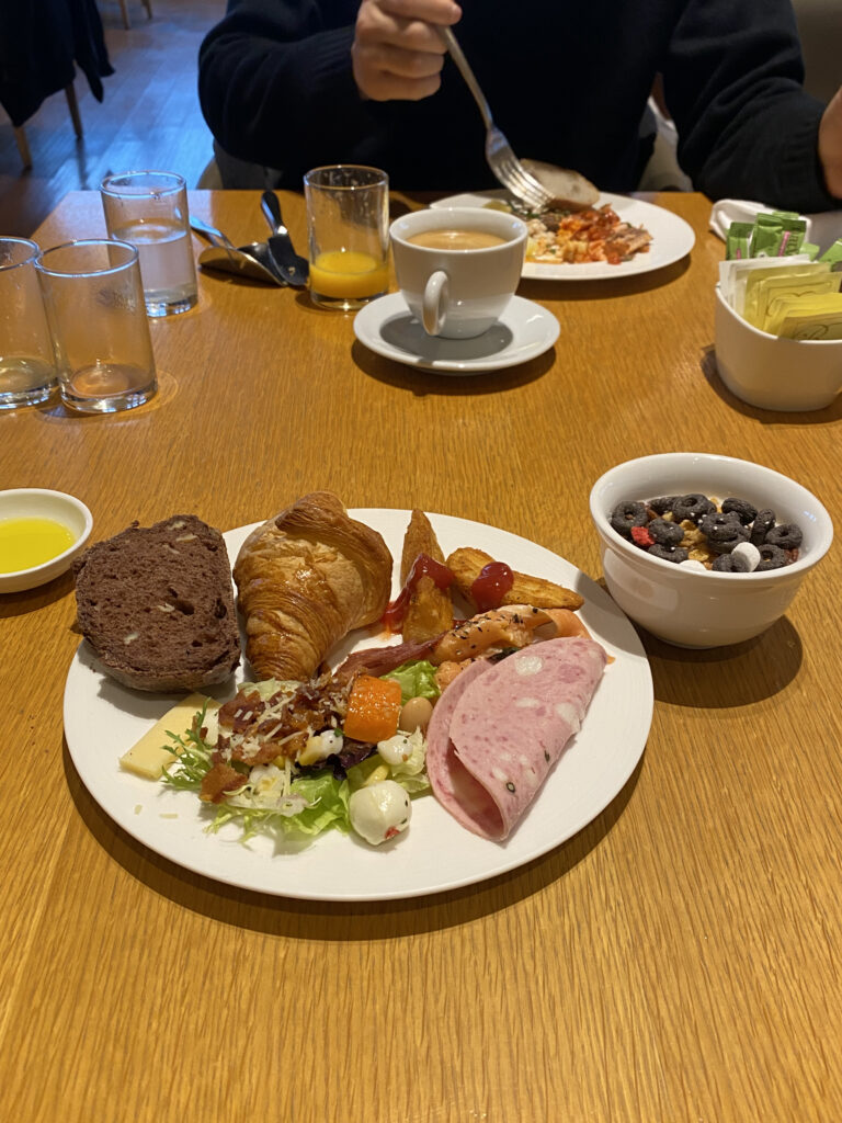 Bread and salad plate. Croissants, chocolate bread, salad, ham, potato wedges, even cereal